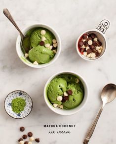 three bowls filled with green ice cream next to spoons on a marble counter top