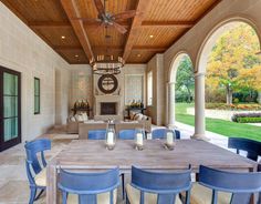 an outdoor dining area with blue chairs and wooden table surrounded by arches that lead into the back yard