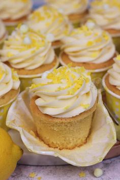 cupcakes with white frosting and yellow sprinkles are on display