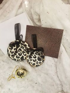 two leopard print purses sitting on top of a white sheet next to a card