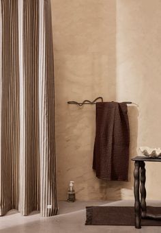 a bath room with a shower curtain and a towel hanging on the wall next to a table