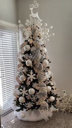 a white christmas tree decorated with silver and white ornaments