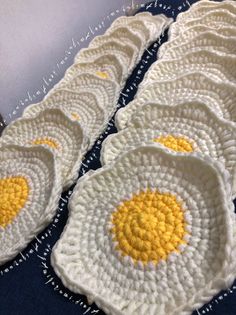 four crocheted eggs sitting on top of a blue tablecloth next to each other