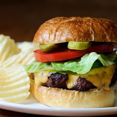 a cheeseburger with lettuce, tomato and pickle slices on it