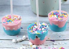 three cake pops with sprinkles and marshmallows on them sitting on a table