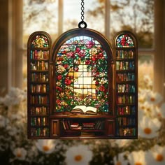 a stained glass window hanging from a chain in front of a book shelf filled with books