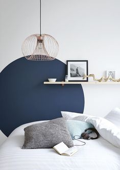 a bed with white sheets and pillows in front of a blue accented headboard