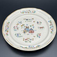 an oval platter decorated with farm scenes and animals, on a gray background is shown