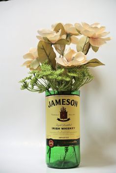 a green bottle filled with flowers on top of a table