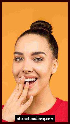 Woman laughing with hand near mouth against an orange background.