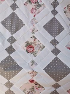 an old quilt with roses on it and grey squares in the middle, along with white polka dots