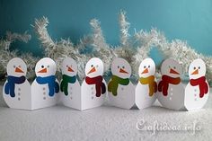 paper snowmen are lined up in front of white branches