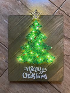 a christmas tree made out of string lights on a wooden plaque that says merry christmas