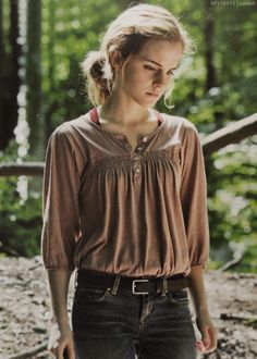 a woman standing in the woods with her hand on her hip and looking at something