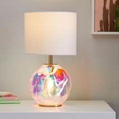 a lamp that is sitting on top of a white table next to a book shelf