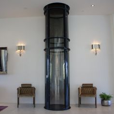 a tall black tower sitting in the middle of a living room next to two chairs