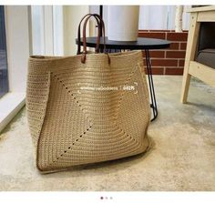 a large straw bag sitting on top of a floor next to a table and chair