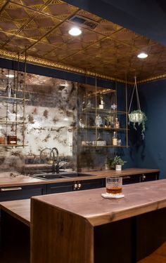 a kitchen with blue walls and wooden counter tops next to a bar area that has shelves on the wall