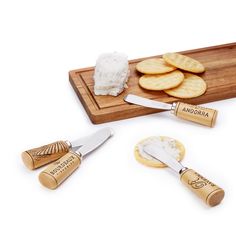 some crackers and cheese on a wooden cutting board with two knifes next to them