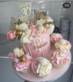 a pink and white cake with cupcakes on top