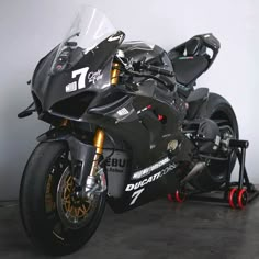 a black motorcycle parked in a garage next to a white wall and some red wheels