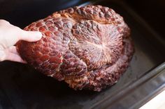 a person is holding up a piece of meat in the air frying pan with it's skin