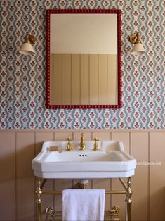 a white sink sitting under a bathroom mirror next to a wall mounted faucet