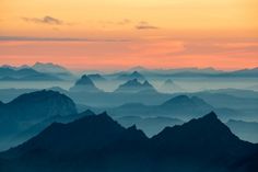 the mountains are covered in fog as the sun is setting over them and there is no image to provide a caption for