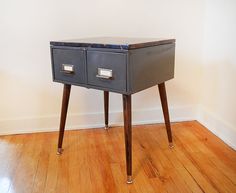 a small table with two drawers on top of it in the corner of a room