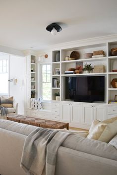 a living room filled with furniture and a flat screen tv sitting on top of a wooden shelf