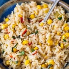 a blue bowl filled with rice and corn on top of a table next to a fork