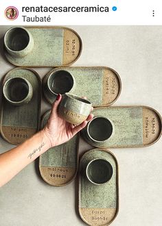 a person is holding a cup in front of several coffee mugs on trays