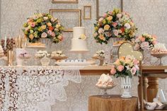 a table topped with cakes and flowers on top of a wooden table covered in doily