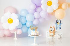 a table topped with cake next to balloons