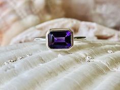 This classic east west bezel setting contains a beautiful 2.00 ct. genuine emerald cut amethyst. The emerald cut stone measures approximately 8x6mm. The ring is available in a satin or high polish finish. The ring is available in sterling silver, and 14k white, yellow, or rose gold. Amethyst is the birthstone for February. Please send me a message if you need a size not listed. * This ring can be customized with any color center stone. All items are handmade by me in my shop in Woodbridge, NJ. P Classic Purple Amethyst Ring With Bezel Setting, Classic Amethyst Ring With Bezel Setting, Classic Amethyst Rings With Bezel Setting, Classic Octagon Amethyst Ring As Gift, Classic Octagon Amethyst Ring For Gift, Classic Emerald Cut Solitaire Amethyst Ring, Classic Octagon Amethyst Ring As A Gift, Classic Amethyst Promise Ring With Bezel Setting, Classic Amethyst Ring With Bezel Setting For Promise