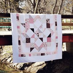 a quilt hanging on a bridge over a stream