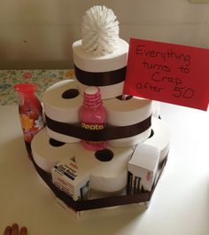 a three tiered cake decorated with toilet paper and a sign that says everything turns to crap after 50