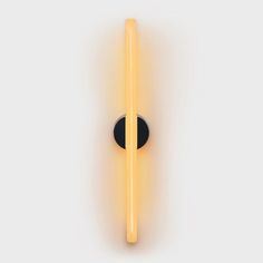 a black and yellow light is on the wall next to a round object that has two sticks sticking out of it