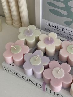 several candles are arranged in the shape of flowers on a table next to a book