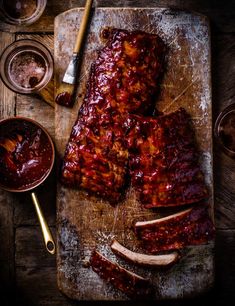 ribs covered in bbq sauce sitting on a cutting board next to condiments