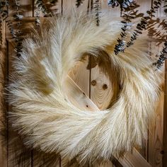 a wreath with white fur hanging on a wooden wall