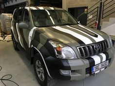 an suv parked in a garage with stripes painted on the front and side of it