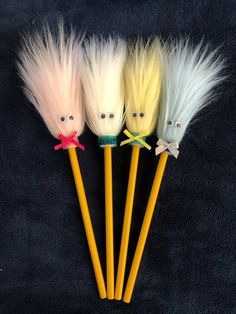 three different colored tooth brushes with fake hair on the top and one has a face drawn on it