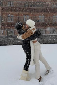 two people standing in the snow hugging each other