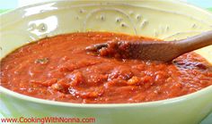 a wooden spoon in a bowl of red sauce