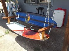 a surfboard sitting on top of a swing in front of a house next to a chair