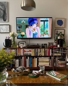 there is a television that is on in the living room with bookshelves and vases