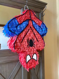 a spiderman pinata hanging from the side of a door with its eyes closed