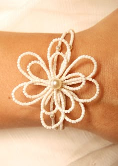 a woman's arm with a white beaded flower bracelet on top of it