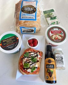 an assortment of food including bread, cheese and berries on a white plate next to other items